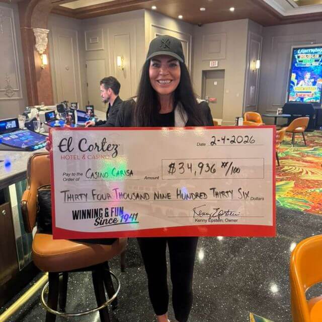 Woman holding large casino check for $34,936.37, standing in a casino with slot machines in the background.